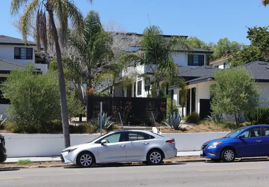 Picture of cars parked along street in front of multi unit housing 