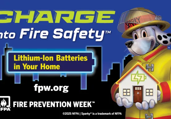 Sparky the Fire Dog, wearing yellow firefighter gear, holds a model of a home in his hands with a city skyline in the background. The image promotes Fire Prevention Week 2025 with the theme “Charge into Fire Safety,” highlighting lithium-ion battery safety at home.