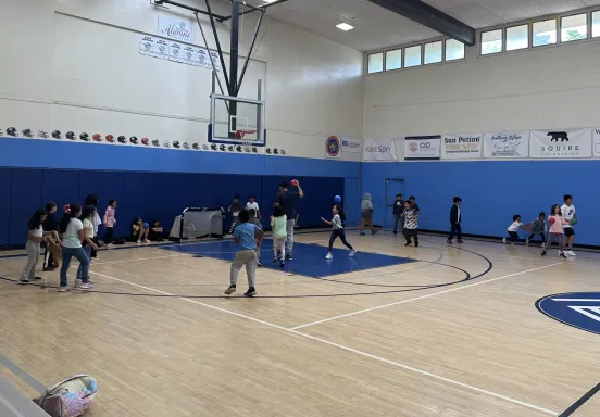 Many children in a gymnasium laughing and playing games with one another 
