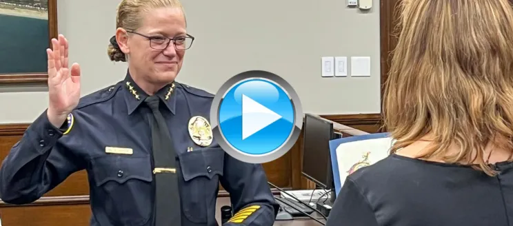 Chief Kelly Ann Gordon taking the Oath of Allegiance with her right hand in the air in her police uniform in Council Chambers