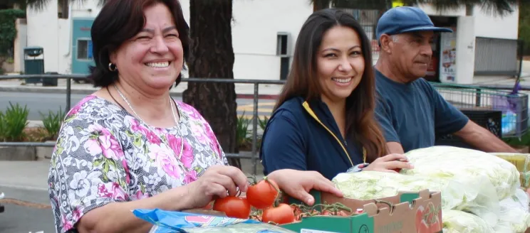 Three people smiling and handing out food.