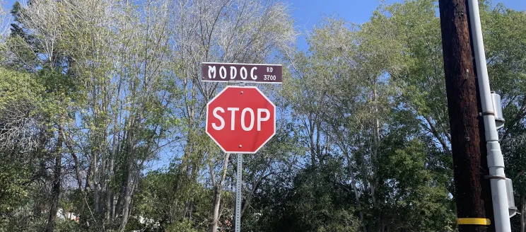 A stop sign below the street sign that says Modoc