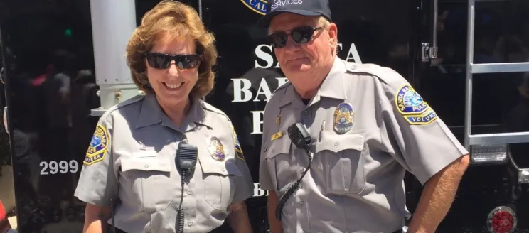 This image shows two members of the Volunteers in Policing program in uniform smiling