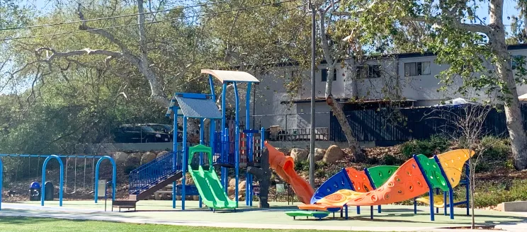 Image shows playground equipment in primary colors at a local park