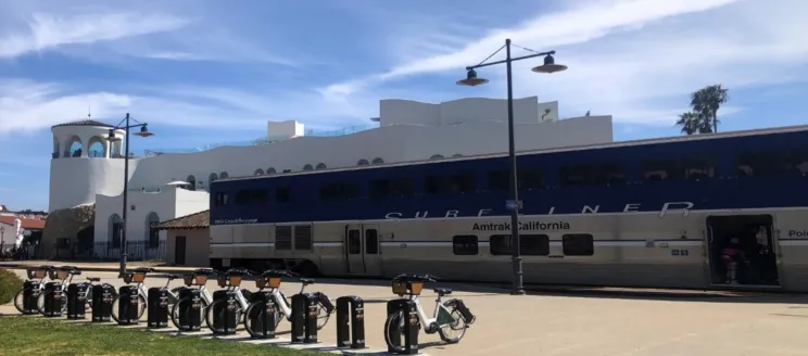 Image shows a row of ebikes in front of the Surfliner train