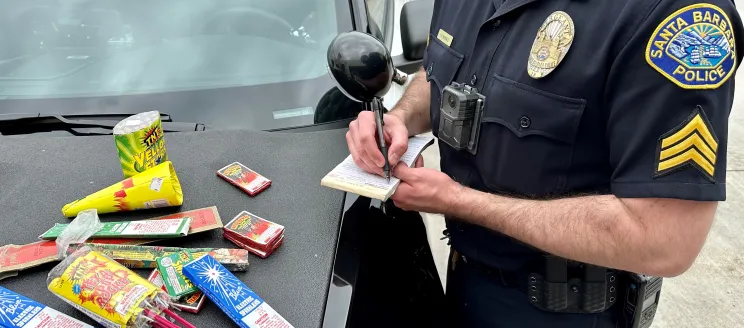 An SBPD officer writes a ticket with fireworks on the dashboard