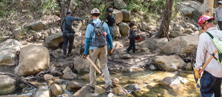 Volunteers hike with tools for trail restoration