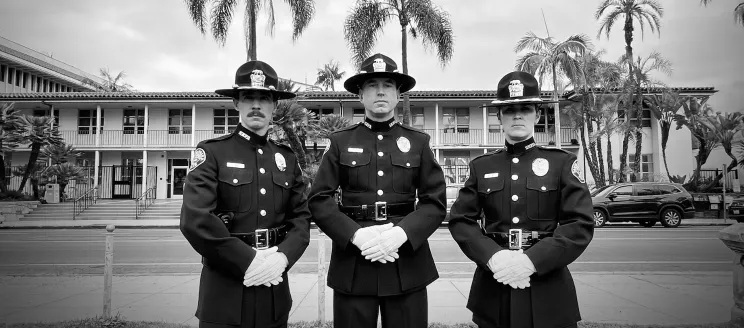 Image shows three officers in uniform solemnly looking at the camera, black and white photo