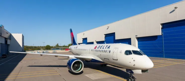 Delta airplane facing forward parked outside an airport hangar