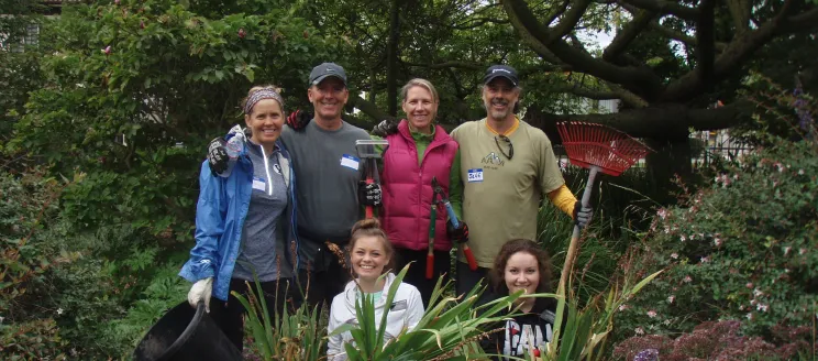 A group of volunteers pose for a picture in Alice Keck Park Memorial Garden with rakes in hand