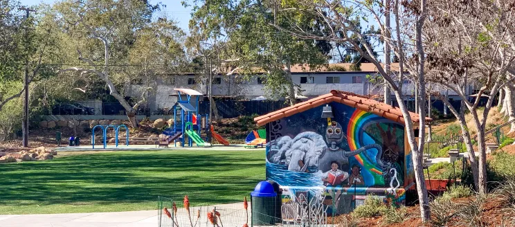 Image shows a City Park with a mural and playground equipment.