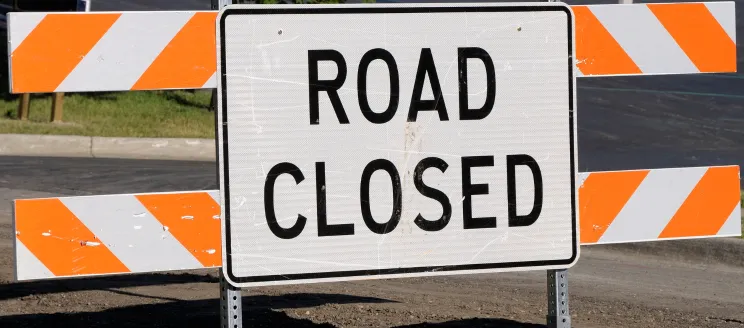 Image of an orange and white sign that reads "Road Closed" 