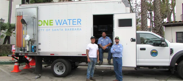Public Works employees standing in front of a One Water service truck.