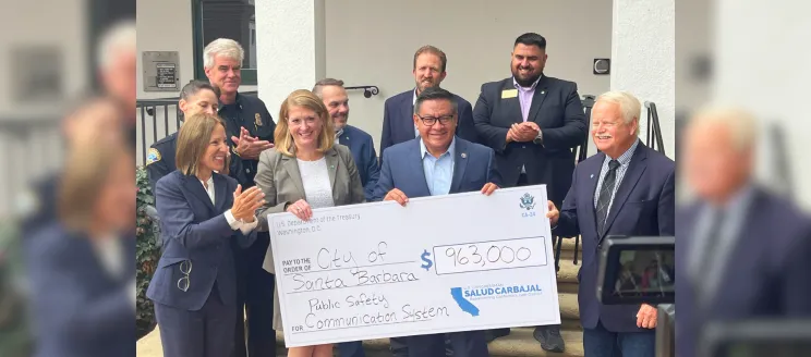 Kelly McAdoo and Rep Carbajal holding a large check surrounded by representative from City Fire-Police-Information Technology