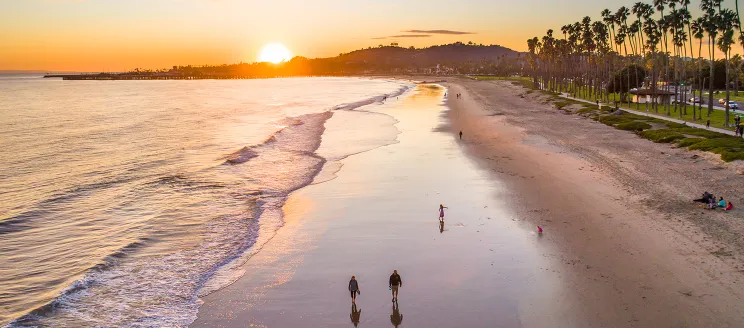 Beach at Sunset with people walking along the sand and pedestrian path.