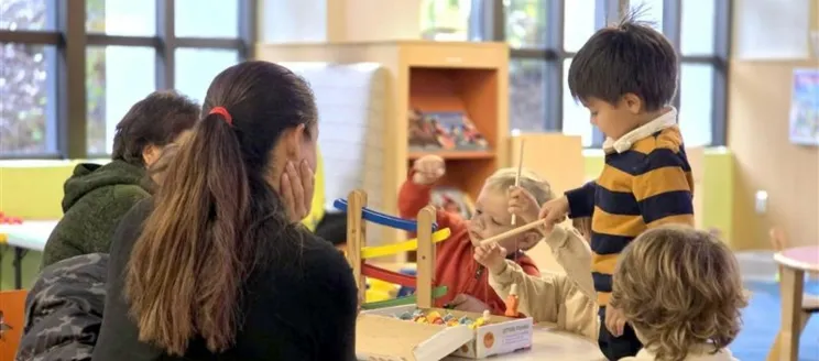 Children Playing with a toy on a table as an adult supervises.