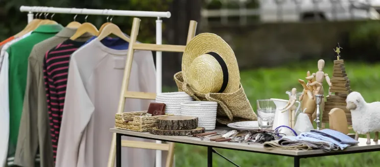 clothing, accessories and housewares on a table  for a yard sale.