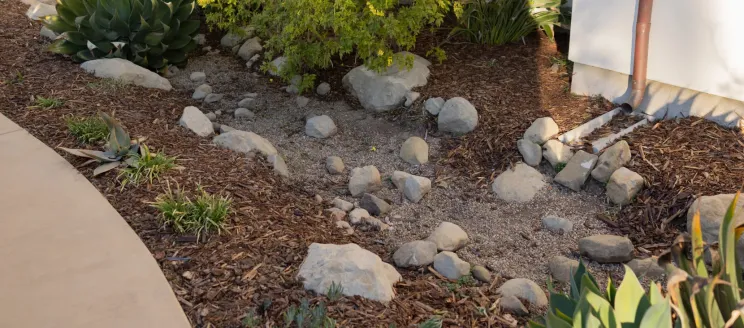 Photo of downspout emptying to gravel that helps with storm water management and run off.
