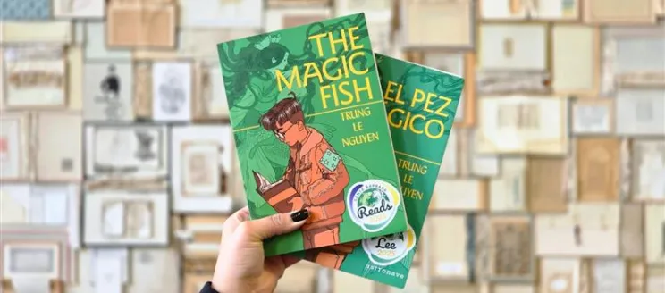 Hand holding the books The Magic Fish and El pez mágico