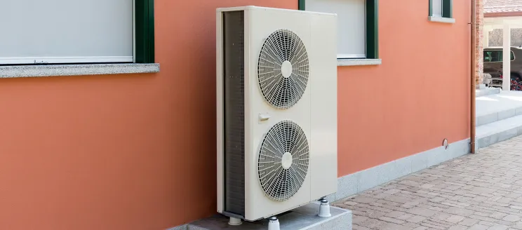 Outdoor heat pump unit with two large fans installed on a concrete base