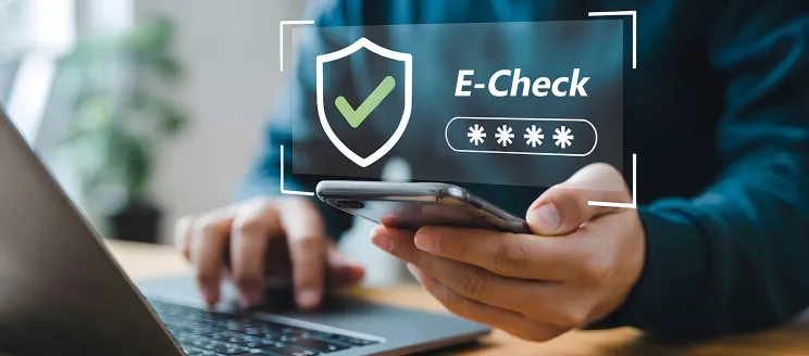 Person paying a bill online with a Smartphone and laptop