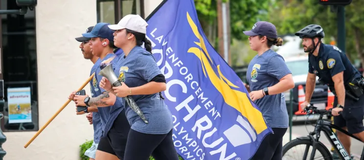 members of local law enforcement agencies run while carrying torch in symbolic support of special olympics