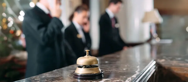 bell on the counter of a hotel check-in desk with staff in the background