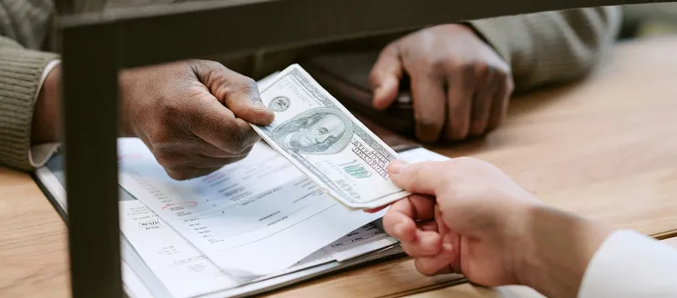 Person paying a bill at a counter with cash