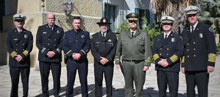 Six uniformed public safety officials pose together outside the Santa Barbara County Courthouse during the 9/11 remembrance ceremony, wearing formal dress uniforms and hats.