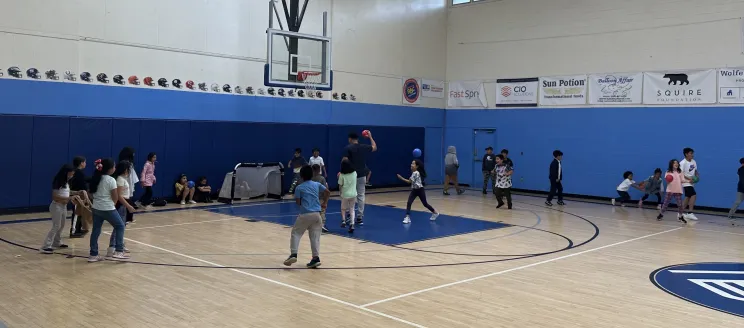 Many children in a gymnasium laughing and playing games with one another 