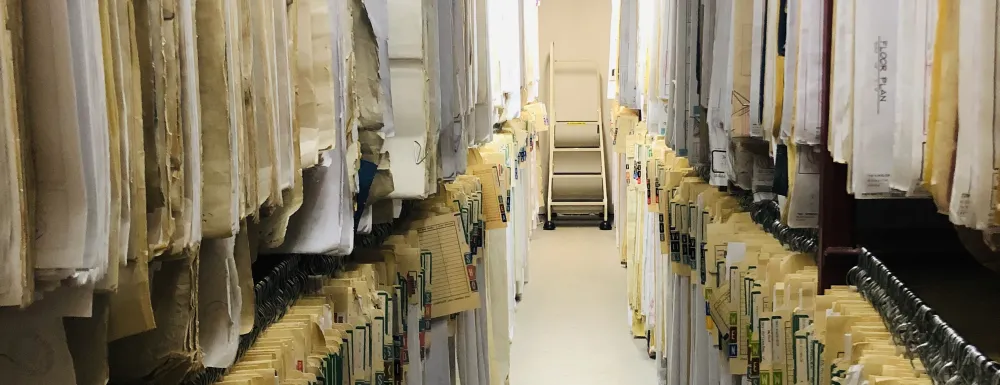 Archive plans hanging on both sides of walk aisle.