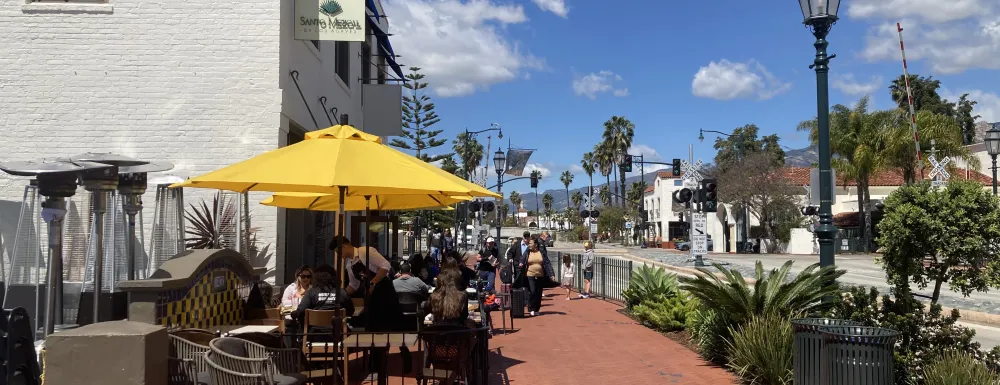 Outdoor dining with a few tables of people being servered by a waiter