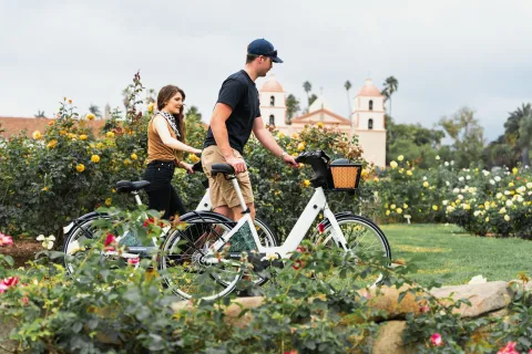 2 People walking their bikes through the Santa Barbara Rose Garden
