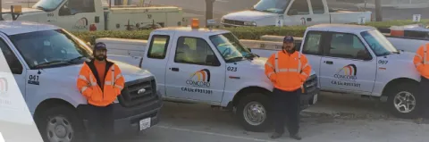 Men wearing orange vests standing in front of trucks for Concord Installation Services