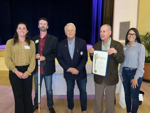 Blind fitness representatives and Mayor Rowse smiling and holding a recognition certificate.