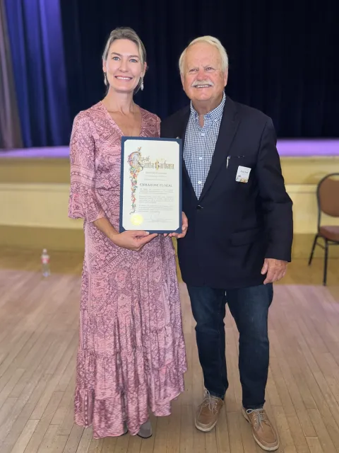 Emmarose Floral owner and Mayor Rowse holding a recognition certificate and smiling.