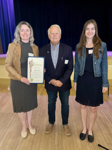 Mayor Rowse and representatives from Trimnasium holding a recognition certificate and smiling 