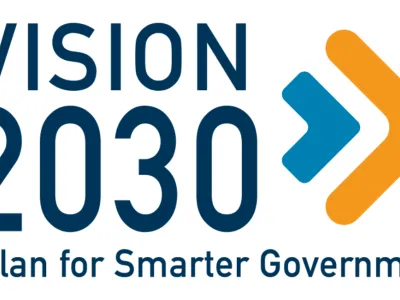 Vision 2030 logo. The words in blue with blue and orange chevron shapes